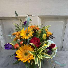 Mixed bouquet with sunflowers, roses, and tulips in a vase