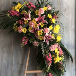 Standing floral spray with pink lilies, yellow daisies, and carnations