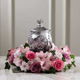 Pink floral arrangement around a silver urn