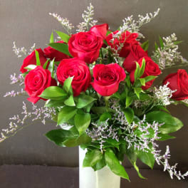 Red roses in a white vase with purple filler flowers
