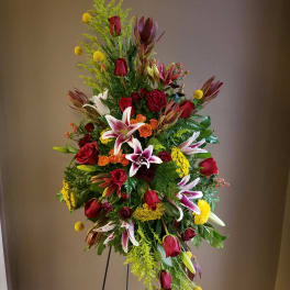 Tall standing floral spray with red roses, lilies, and yellow accents
