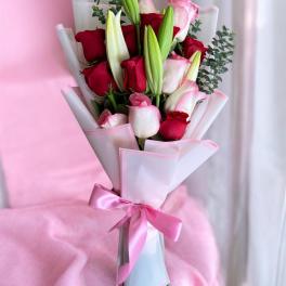 Bouquet of red and pink roses with lily buds wrapped in pink paper