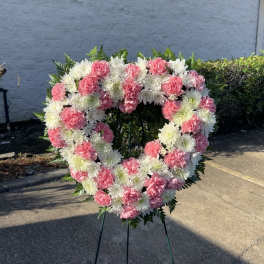 Heart-shaped floral wreath of pink and white flowers on a stand