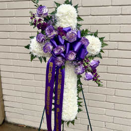 Purple and white funeral spray on a stand with ribbons