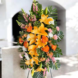 Standing floral spray with orange lilies and pink blooms on a metal easel