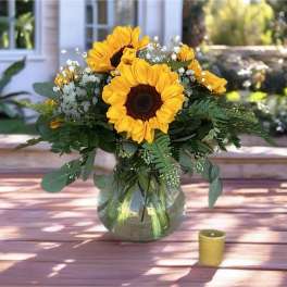 Sunflower bouquet in a glass vase with a small candle nearby