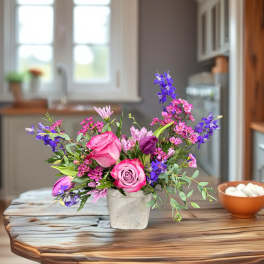 Pink and purple mixed bouquet in a white vase on a wooden table