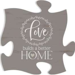 Gray puzzle-piece sign with the words "Love builds a better HOME"