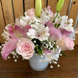 Pink roses and lilies arranged in a white vase