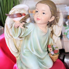 Angel figurine holding a small bird and flower basket