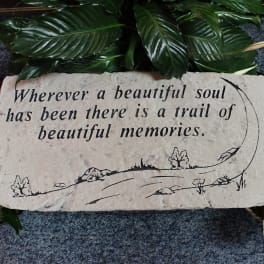 Memorial stone with engraved quote surrounded by green leaves