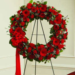 Red floral wreath on a black stand with a red ribbon