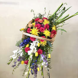 Large mixed flower basket on a stand with bright pink, yellow, white, and purple blooms