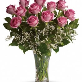 Pink roses arranged in a clear glass vase with white filler flowers