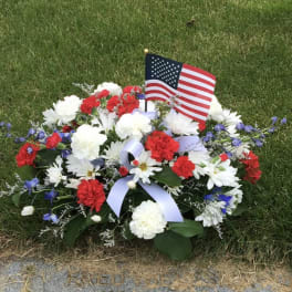 Red, white, and blue floral grave arrangement with an American flag