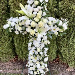 White floral cross standing on a metal easel