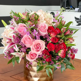 Pink and red roses with lilies in a gold vase