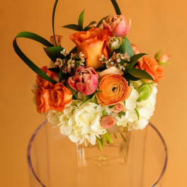 Orange and pink floral basket arrangement in a clear container