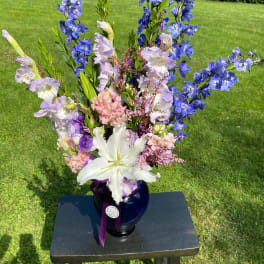 Tall bouquet of blue and lavender flowers in a dark vase