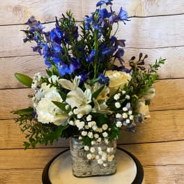 Blue and white floral arrangement in a square glass vase