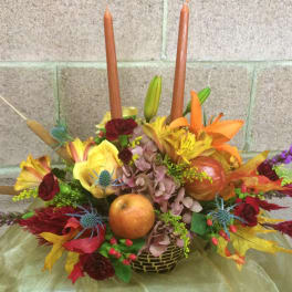 Autumn floral centerpiece with candles and fruit in a low basket