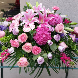 Large pink and purple floral arrangement with lilies, roses, and hydrangeas