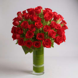 Bouquet of red roses in a tall green glass vase