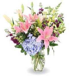 Pink lilies and blue hydrangeas in a clear glass vase