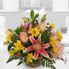 Basket arrangement with pink lilies, yellow daisies, and pale roses