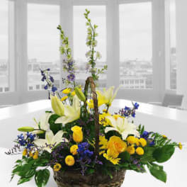 Basket arrangement with yellow and white flowers and tall blue accents