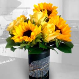 Sunflower bouquet in a black vase with a decorative ribbon wrap