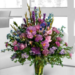 Large mixed purple and pink flower arrangement in a glass vase