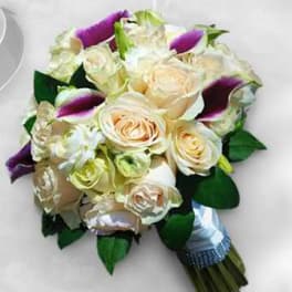 Cream roses and purple calla lilies arranged in a bouquet
