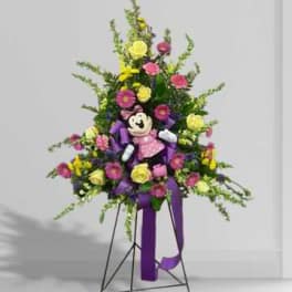 Tall floral standing spray with a teddy bear and purple ribbon