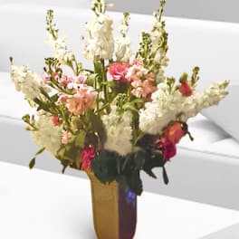Tall floral arrangement with white and pink blooms in a gold vase