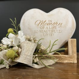 Heart-shaped memorial plaque with a small floral accent and ribbon