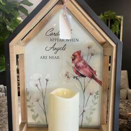 House-shaped memorial lantern with a candle and cardinal artwork