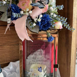 Pink and blue floral arrangement on a rose-gold lantern with a butterfly accent