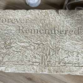Rectangular memorial stone engraved with 'Forever Remembered' and a deer and mountain scene.