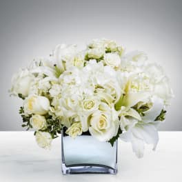 White roses and lilies arranged in a square glass vase