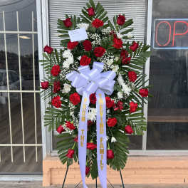 Standing floral wreath with red roses and white flowers on an easel