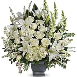 White roses and lilies arranged in a dark urn vase