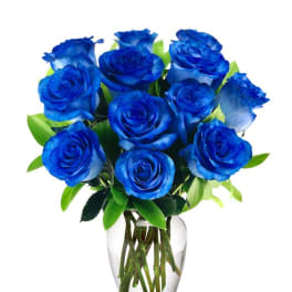 Arrangement of vivid blue roses in a clear glass vase.