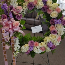 Large floral wreath with pink, purple, and white flowers on a stand