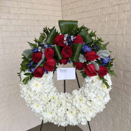 Circular floral wreath with red roses and white chrysanthemums on a stand