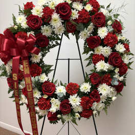 Heart-shaped wreath of red roses, white daisies, and red carnations on an easel