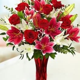 Bouquet of red roses and pink lilies in a red glass vase