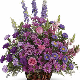 Purple and pink mixed flower arrangement in a wicker basket