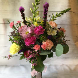 Mixed bouquet in a glass vase with pink, yellow, and peach flowers