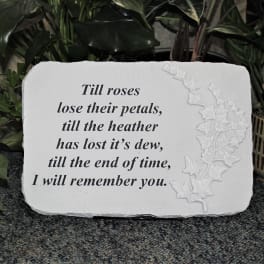 White memorial plaque with an engraved quote and floral relief